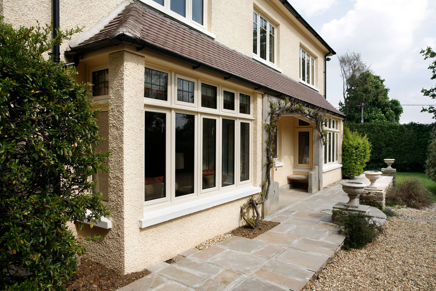 Large property with large replacement windows and a gravel drive and block paving path