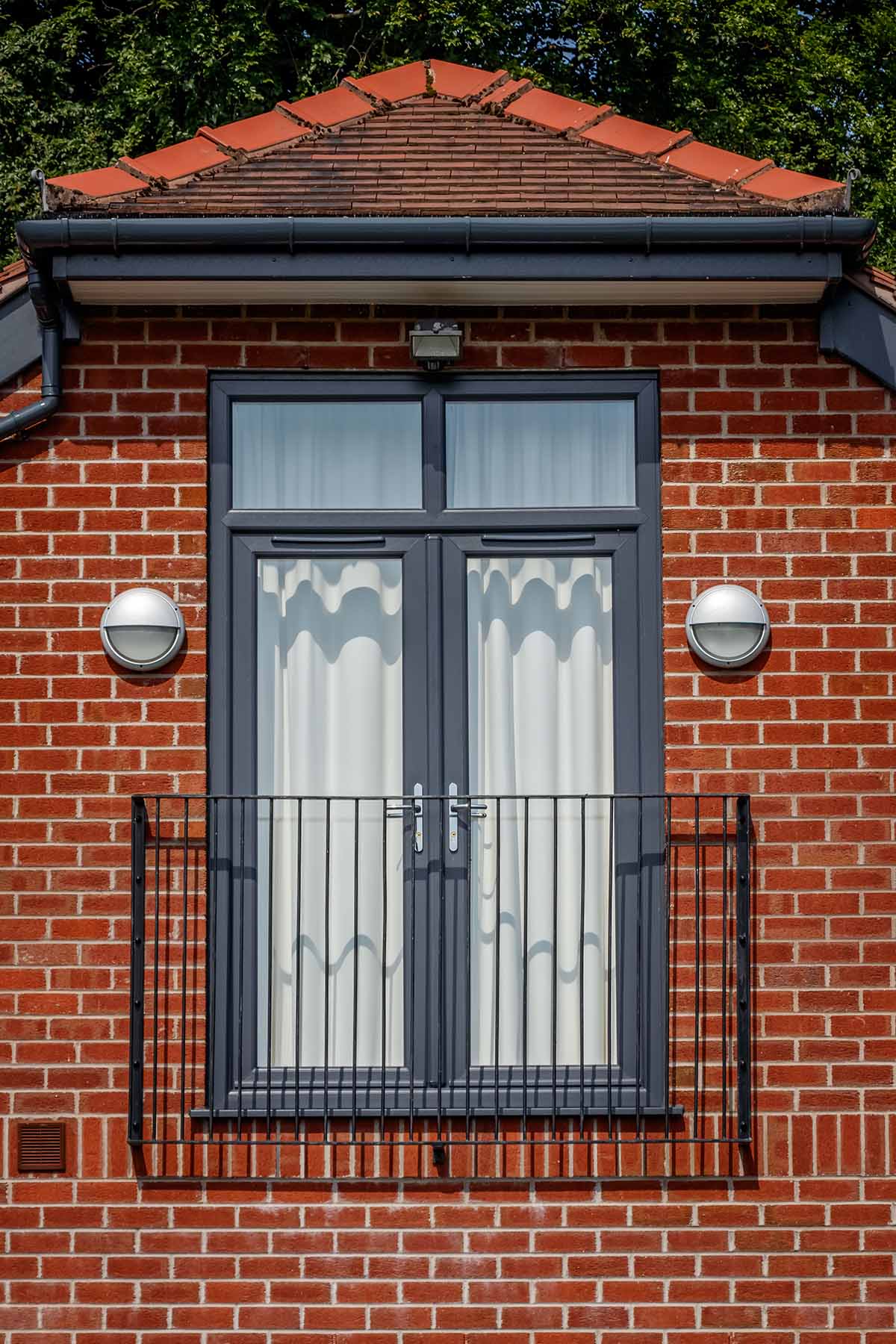 French doors on second floor of a brick home with small balcony