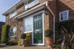 green composite door in modern house with brick porch